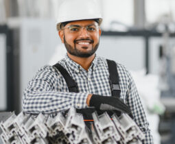 Operator of machine. Industrial worker indoors in factory. Young technician in white hard hat.